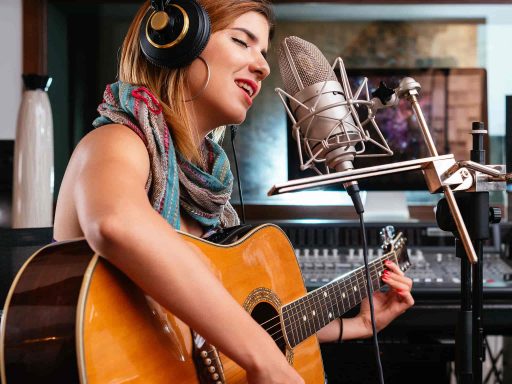 Woman playing a guitar while singing into a microphone